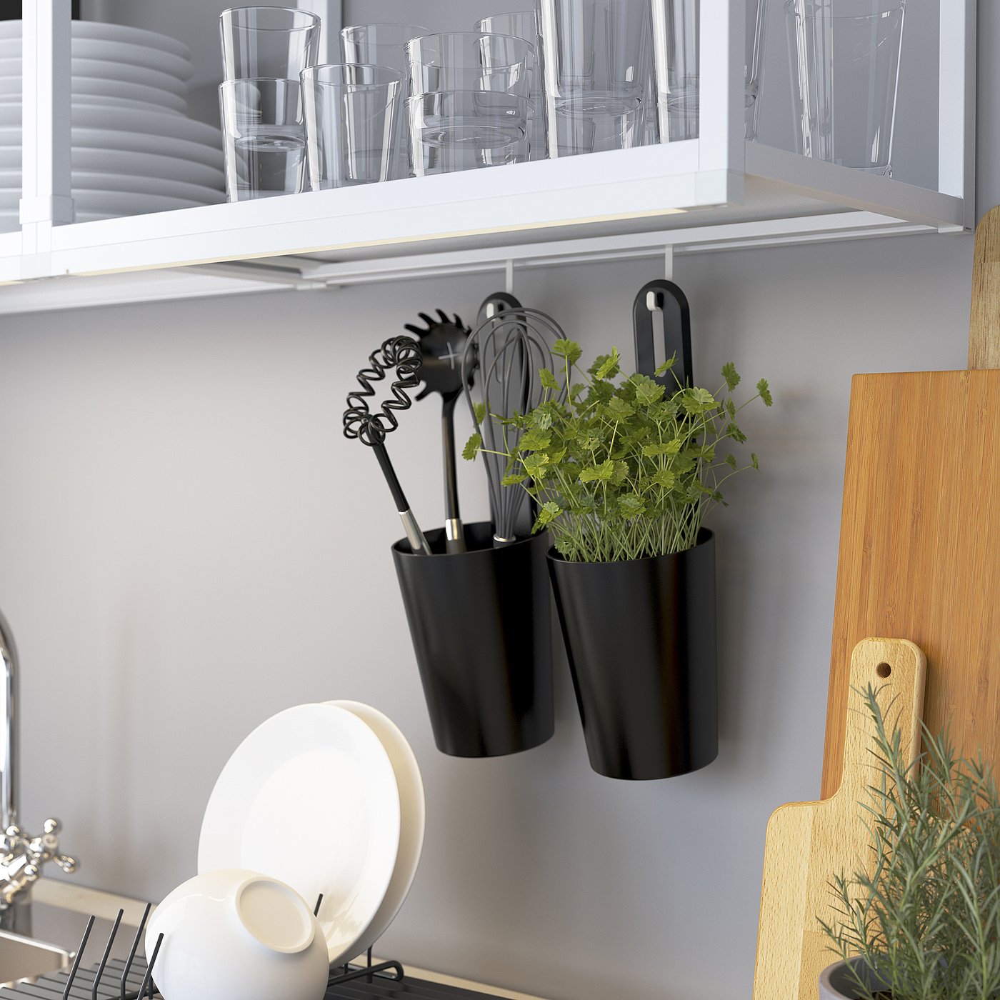 Modern kitchen wall storage showing glasses, utensils, and herbs in hanging black planters.