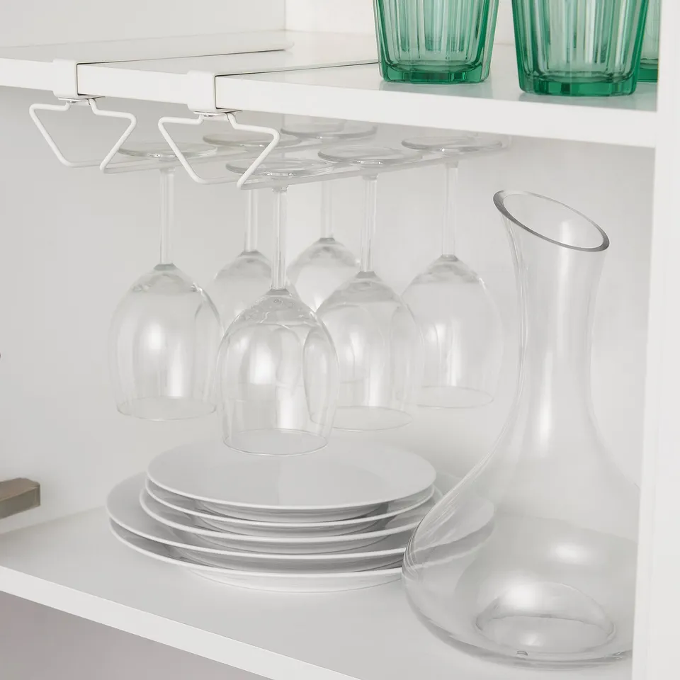 Under-shelf wine glass rack, holding six glasses securely. Below, stacked dishes and a large clear glass.