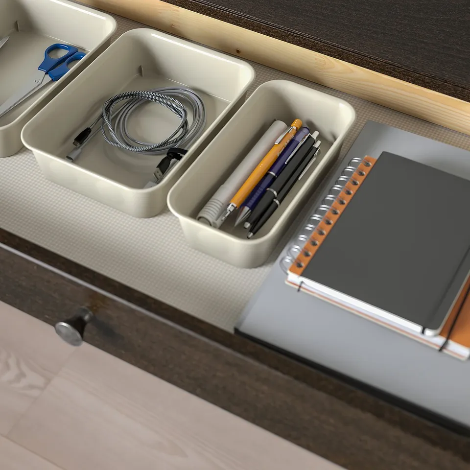 Organised desk with built-in cable management. Drawers hold charging cables, pens, and notebook.