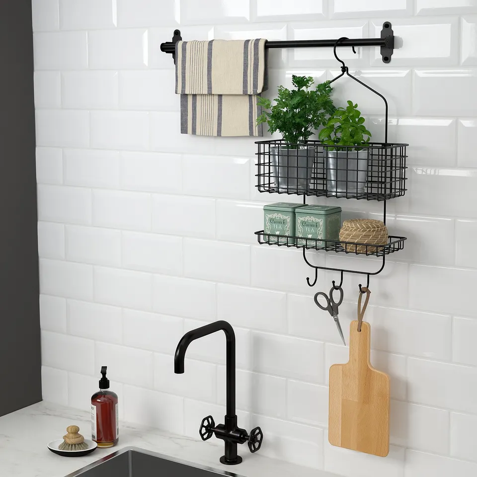 Wall-mounted kitchen shelf with hanging towels, baskets, and hooks. Includes scissors, cutting board, and canisters. Black and white theme.