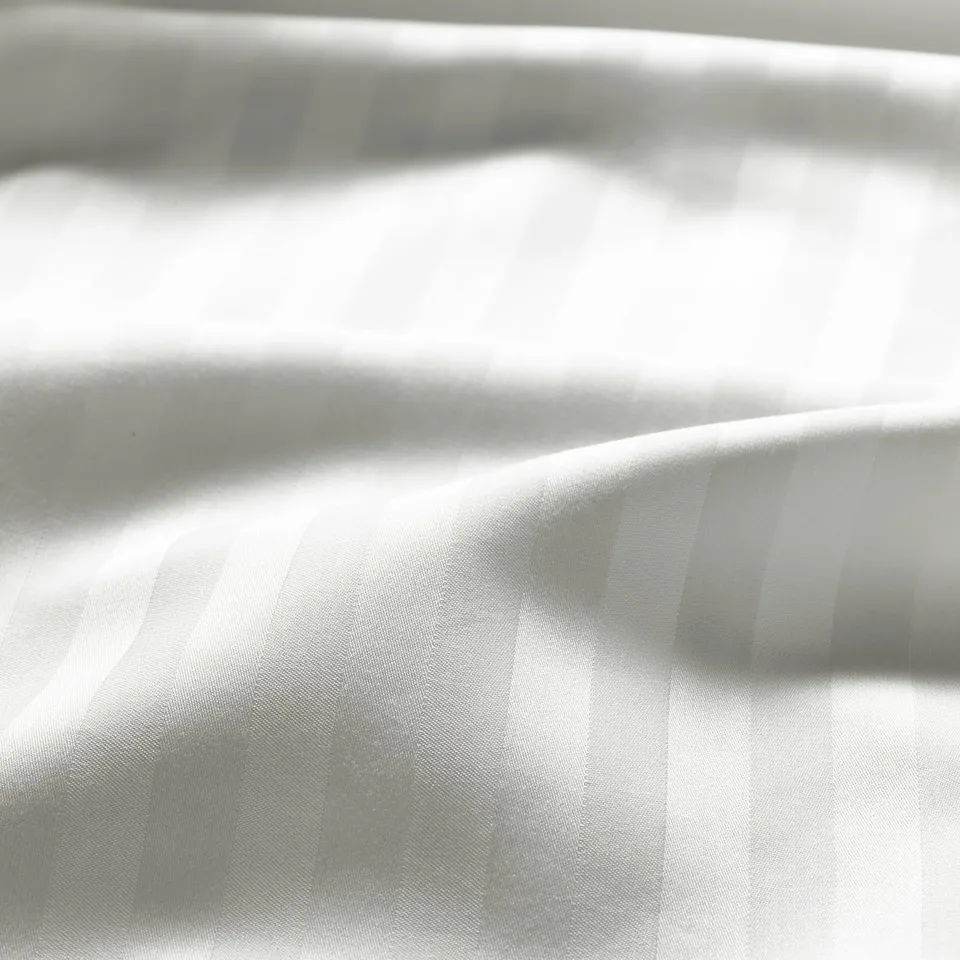 Close-up of smooth, striped duvet cover in sateen weave, showcasing its lustrous, soft fabric quality.