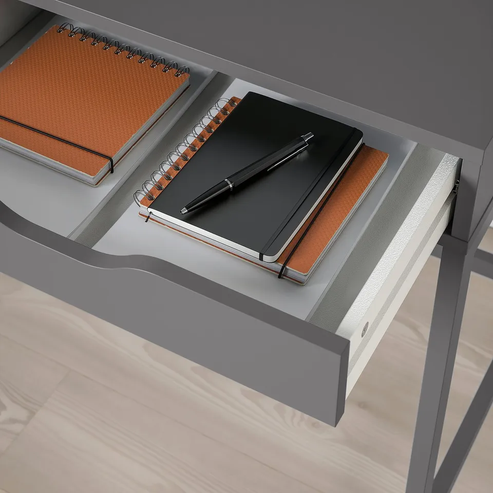 Open desk drawer with neat notebooks and pen, minimalist workspace.