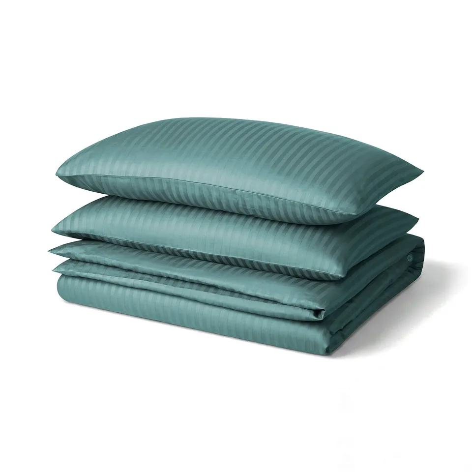 Teal bedding set with two pillowcases and duvet, soft striped texture, neatly folded.