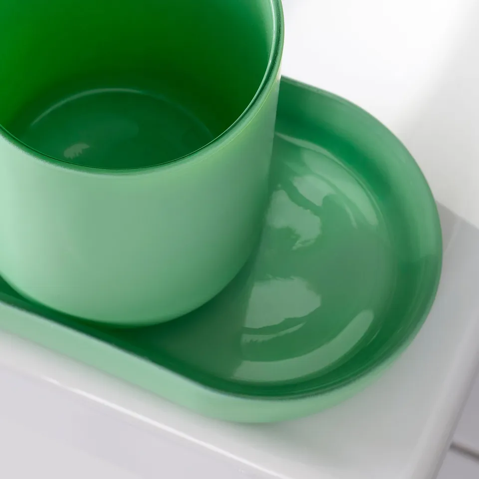 Bright green soap dispenser and tray on white shelf. Smooth, modern design.