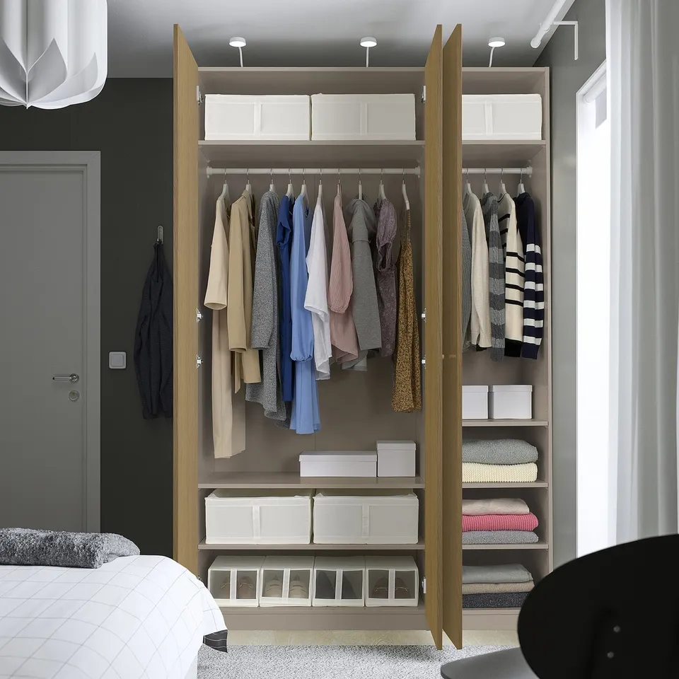Modern open wardrobe with clothes and storage boxes, adjustable shelves and lighting.
