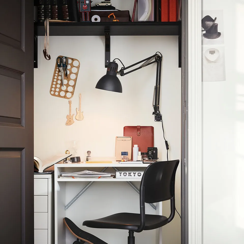 Modern black office chair with height adjustment, textured seat, high back support at white desk.