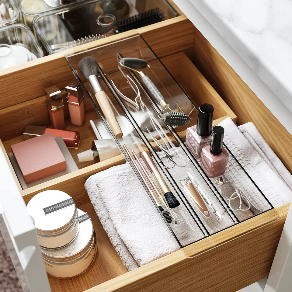 Organised drawer with makeup brushes, tweezers, nail polish, and containers.
