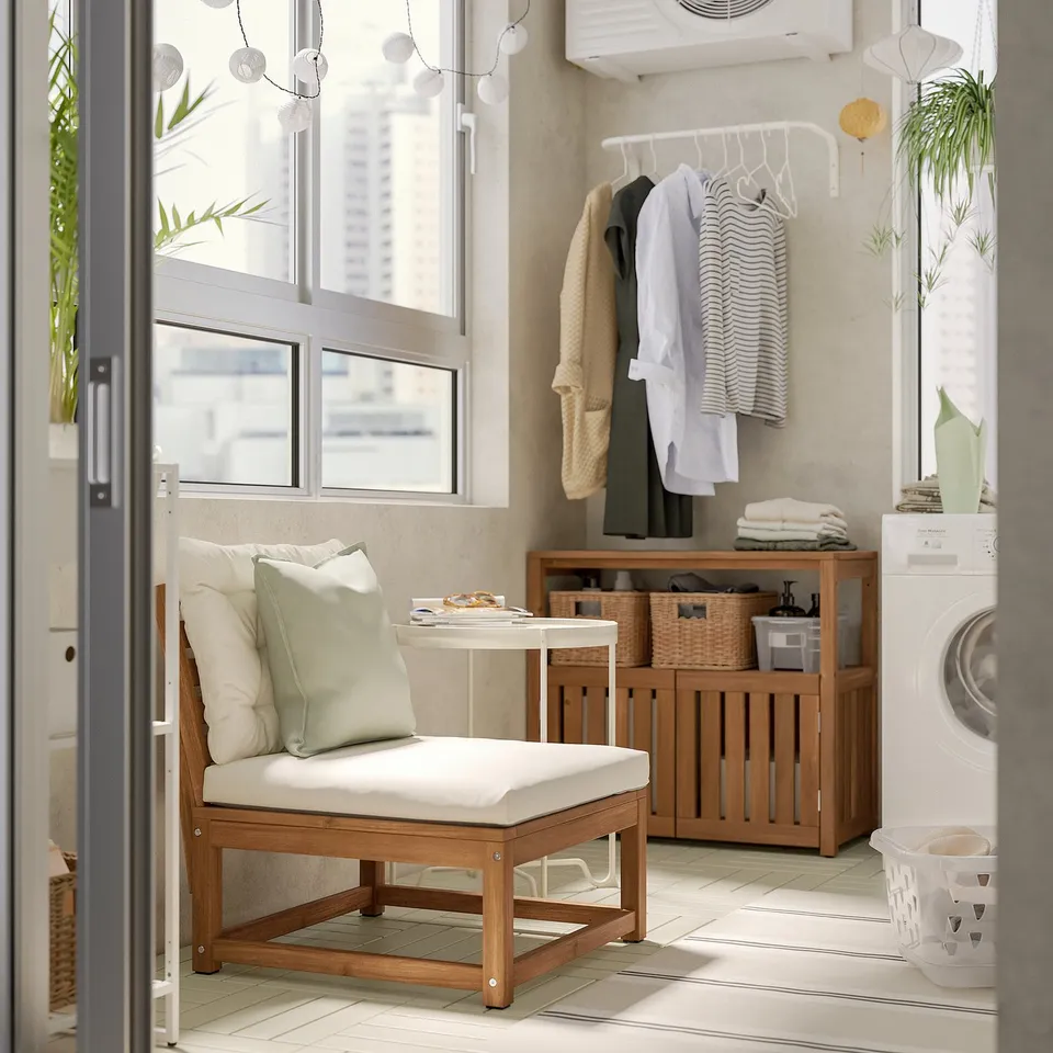 Modern outdoor seating area with beige cushioned wooden furniture, clothes drying rack, and washing machine.