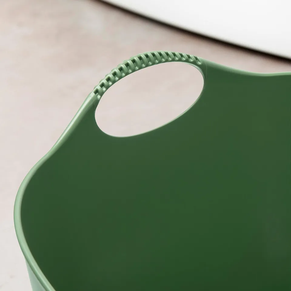 Green plastic laundry basket with textured carry handles, modern design.