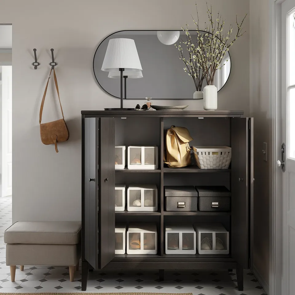 Modern entryway with black IDANÄS cabinet, white lamp, mirror, and hooks. Organised with clear boxes and a beige stool.