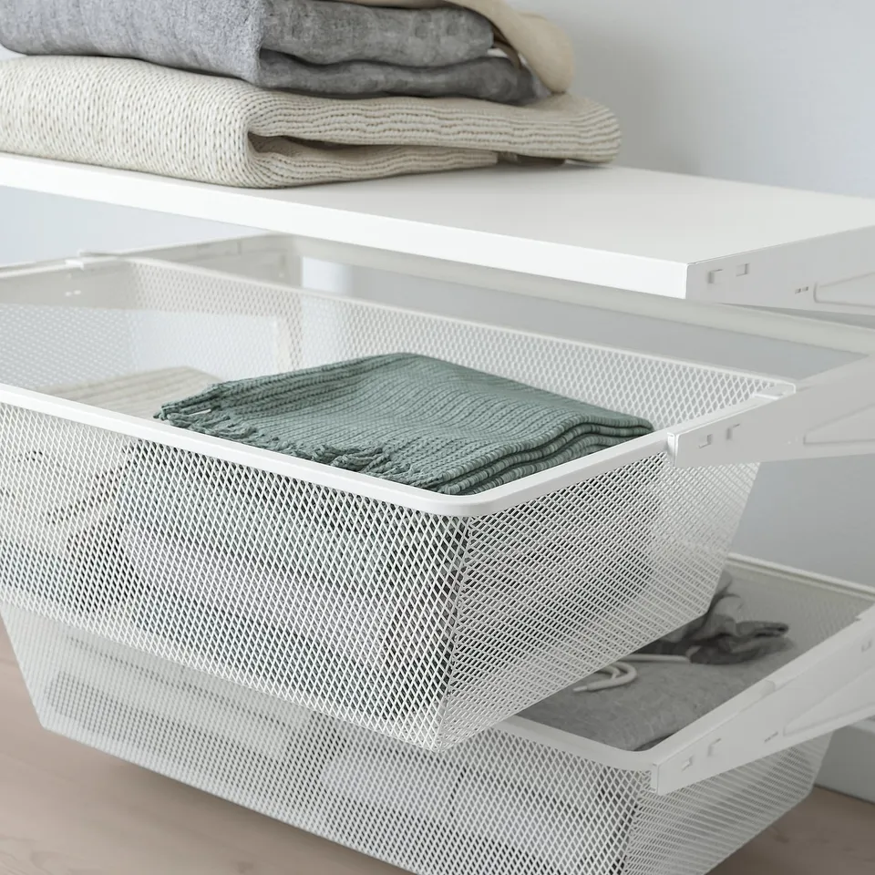 White mesh storage baskets in closet system, holding folded green blanket.