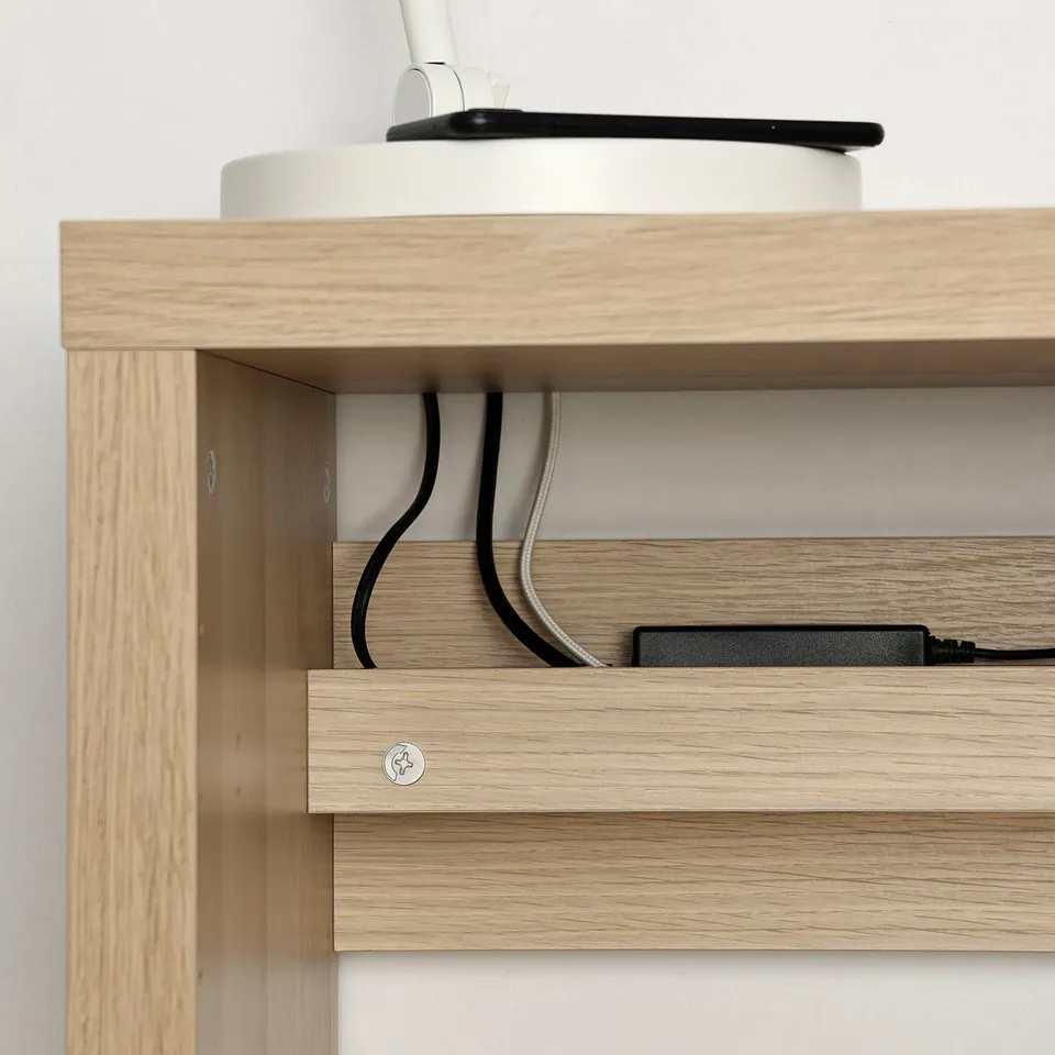 Wooden desk with built-in cable outlet, showing organised cables behind shelves.