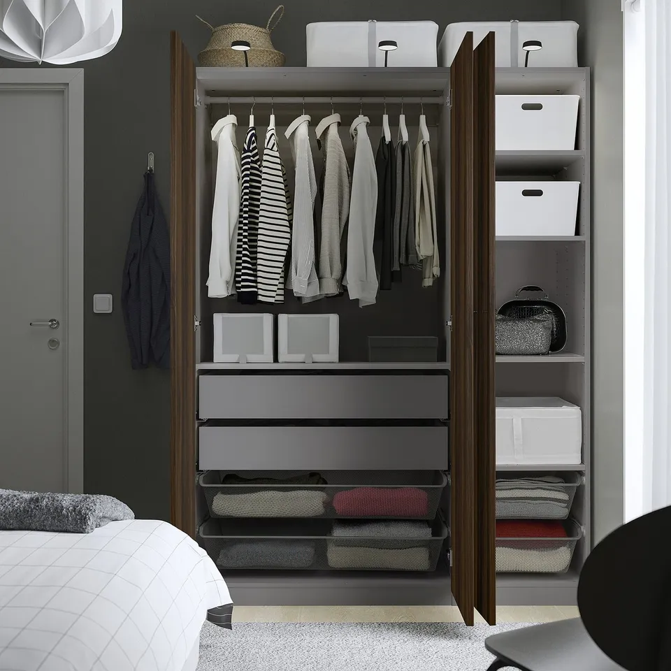 Open wardrobe showing clothes hangers, folded clothes on shelves, and mesh drawers. Its organised with multiple compartments for various items.
