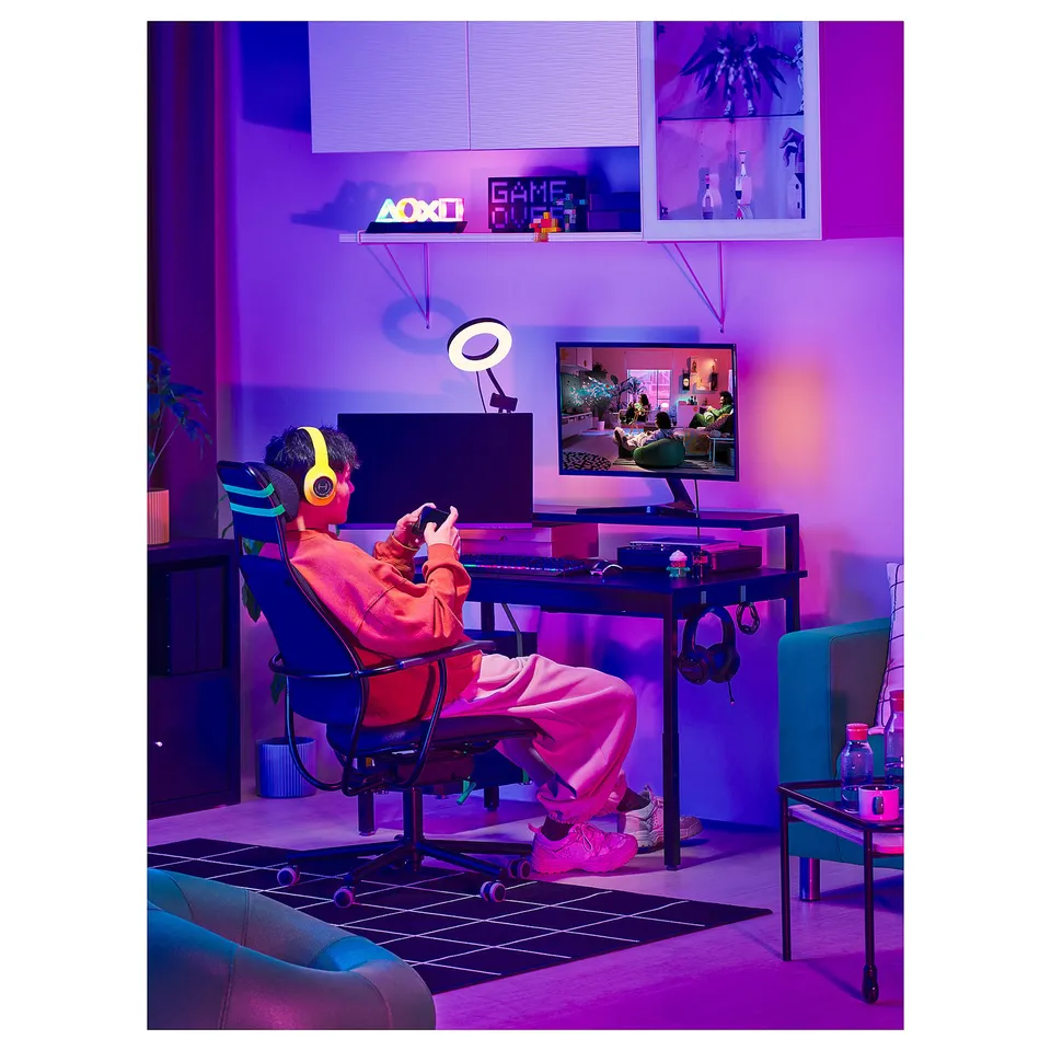 Person gaming at desk with computer, monitor, and neon lights.