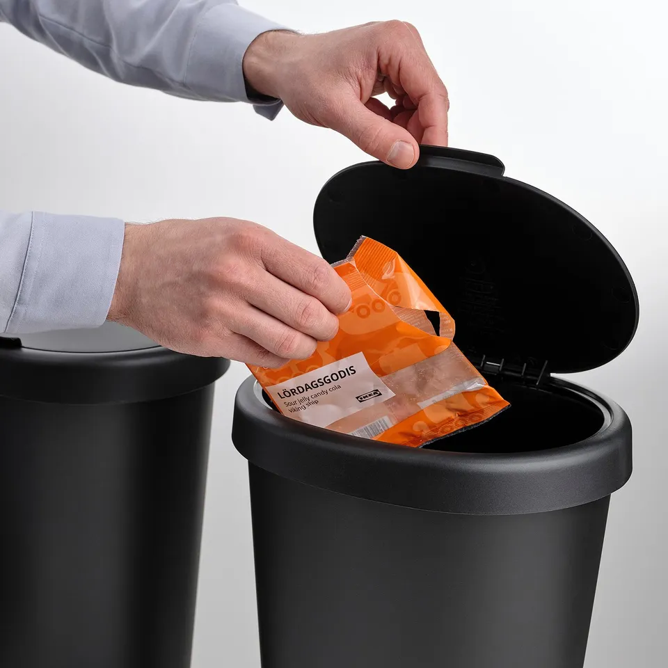 Person discards orange waste into HÖLASS sorting bin with lid open.