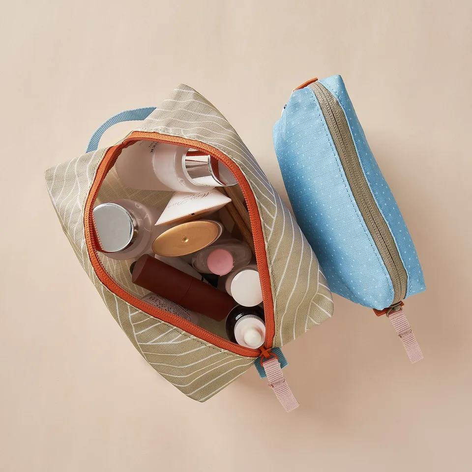 Two accessory bags filled with cosmetics and toiletries, made from recycled polyester, perfect for organising small items.