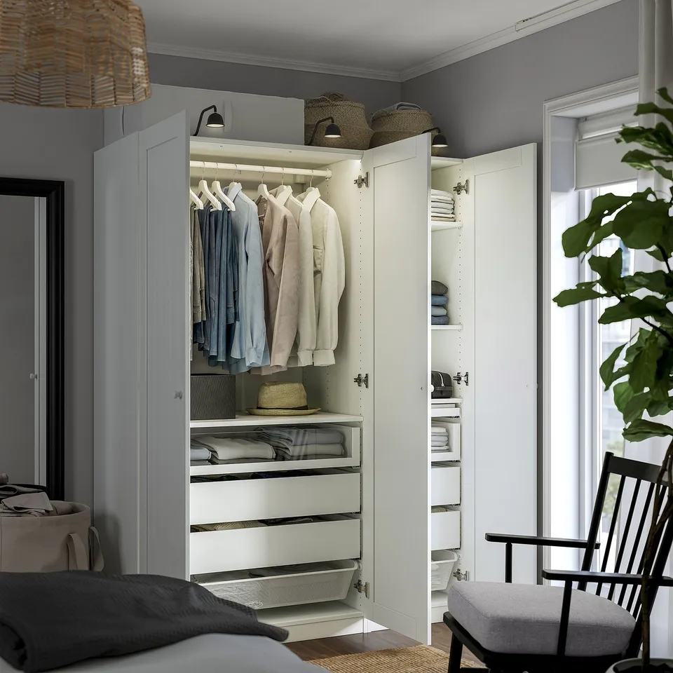 Modern wardrobe with clothes, drawers, and shelves. The built-in lights illuminate the hanging shirts and organised storage solutions.