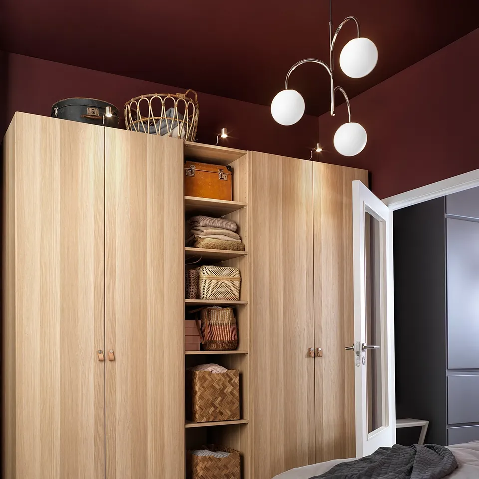 Modern bedroom with light wooden PAX wardrobe, white lights, and grey bedding.