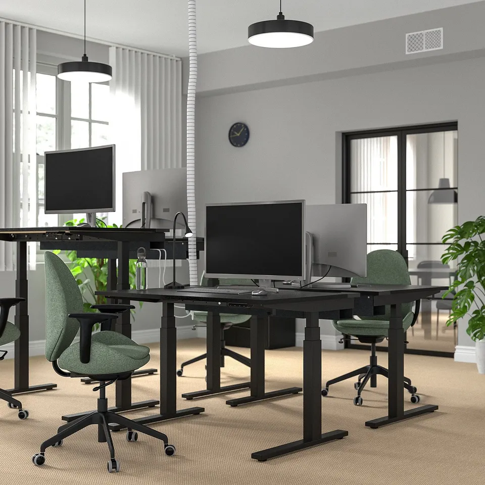 Modern office with MITTZON black sit/stand desks, green ergonomic chairs, dual monitors, plants, and pendant lights.