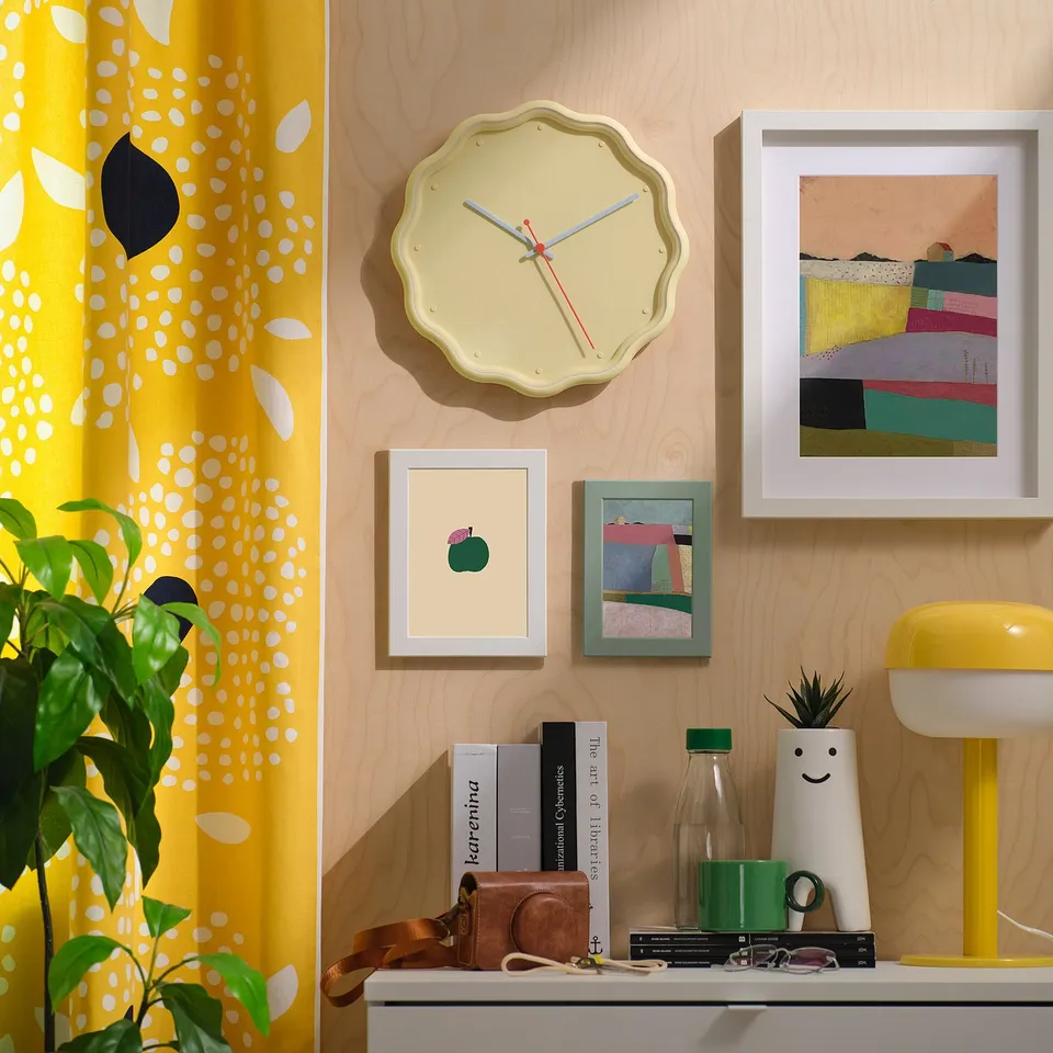 Yellow floral clock hangs above shelf on wood-grained wall.