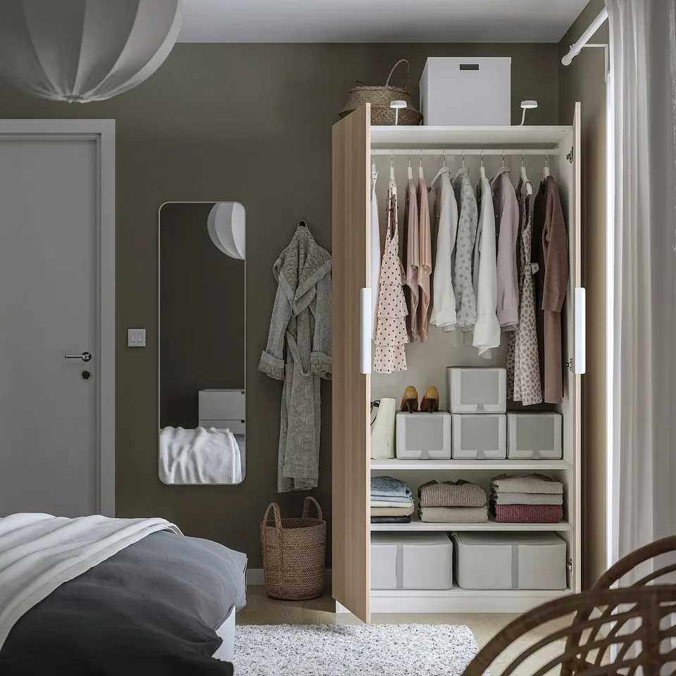 Bedroom with open wardrobe, clothes, folded clothes, and storage bins, hanging robe.