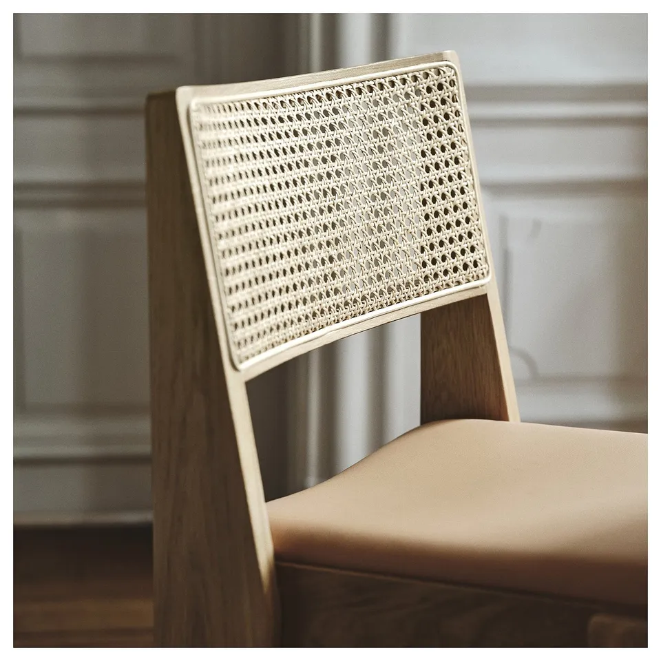 A chair with a sturdy oak frame and a woven rattan backrest, topped with a smooth leather seat, showcasing high-quality materials and craftsmanship.