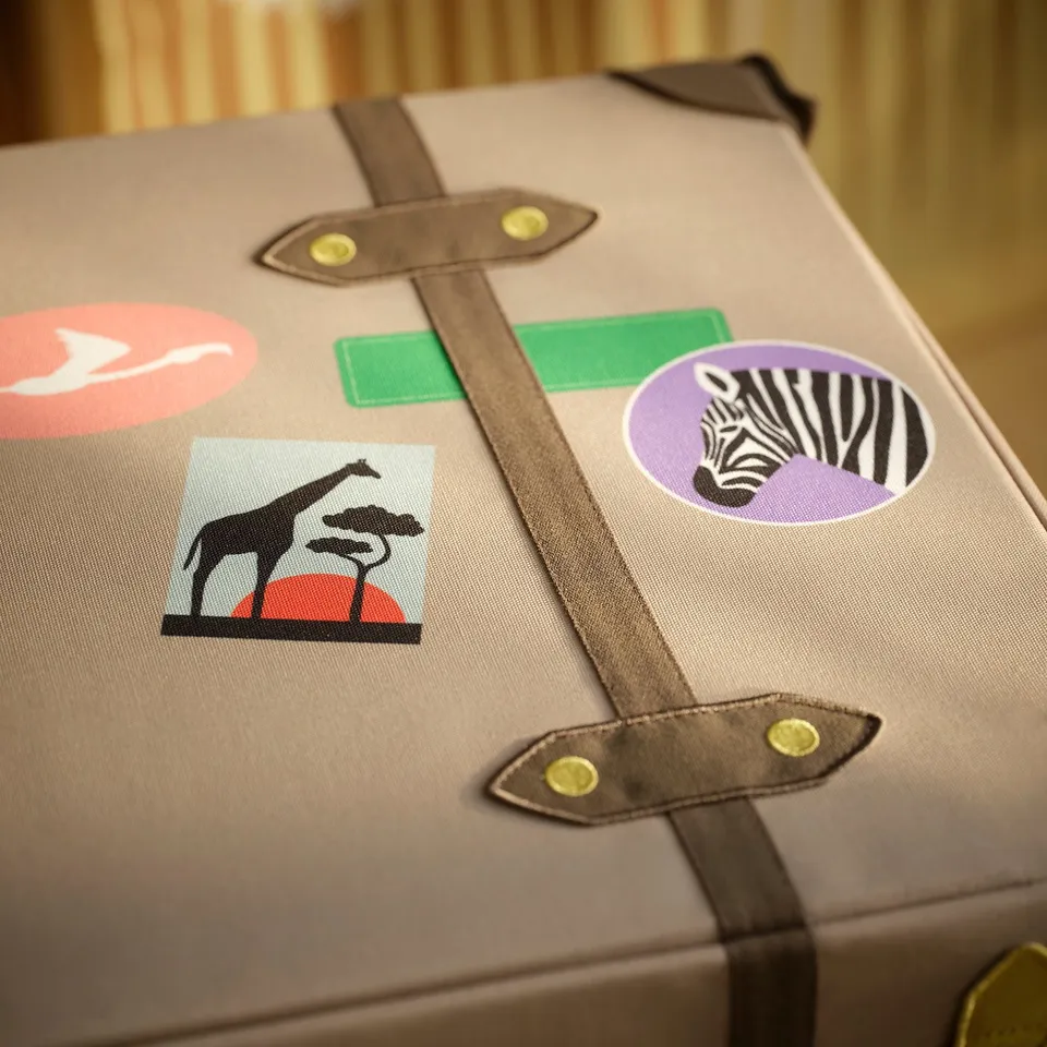 Decorative storage trunk with safari-themed patches; durable, recycled materials.