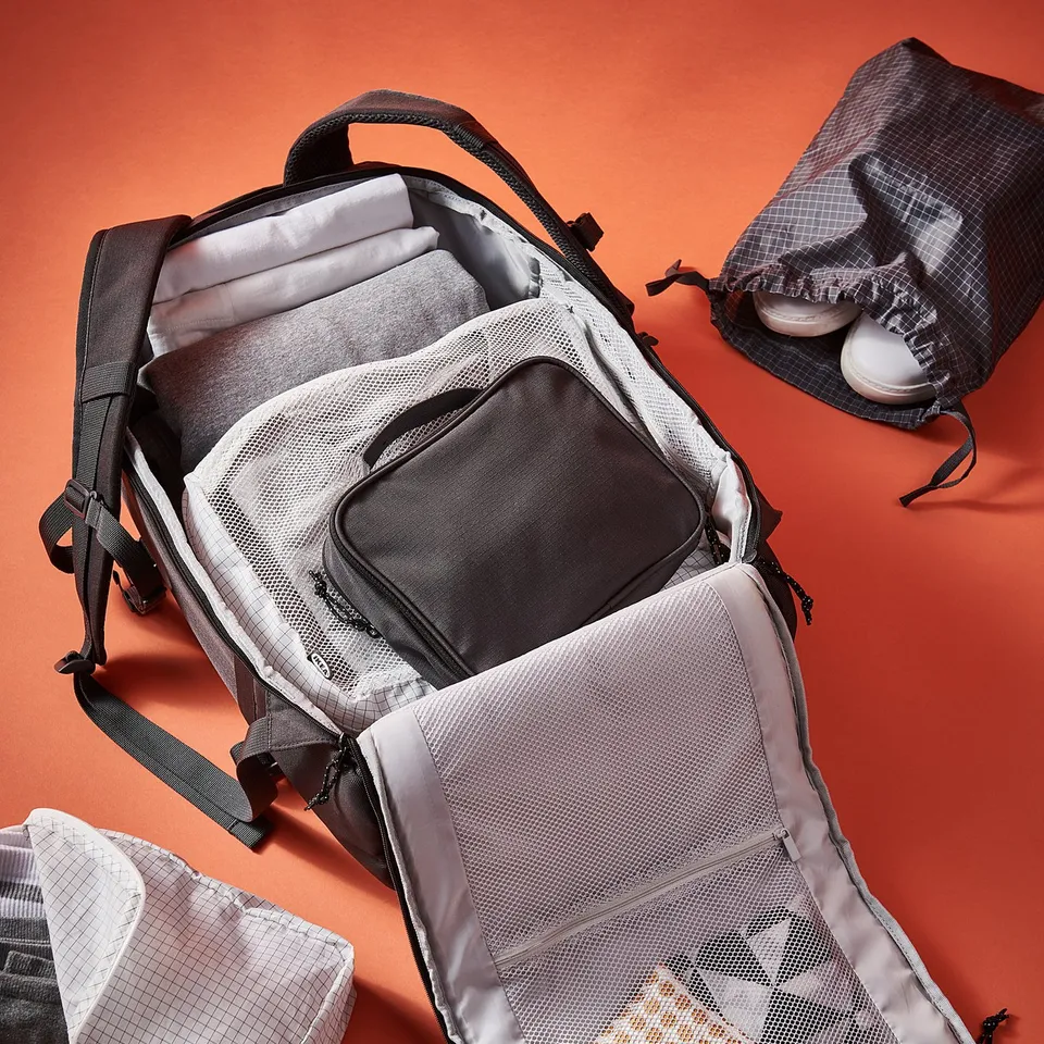 Grey RENSARE travel bag with multiple organisational pockets on orange background.