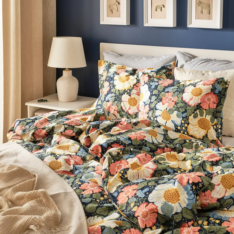 Dark blue floral ARENBOK bed, 50% cotton 50% lyocell, with bedside lamp and art.