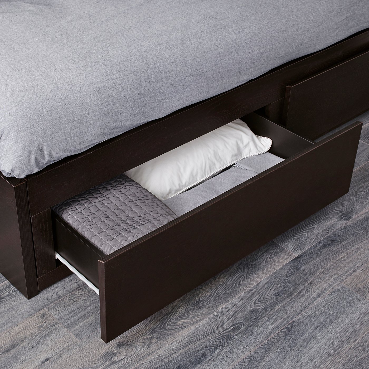 Bed with large open drawer containing pillows, showing storage space.