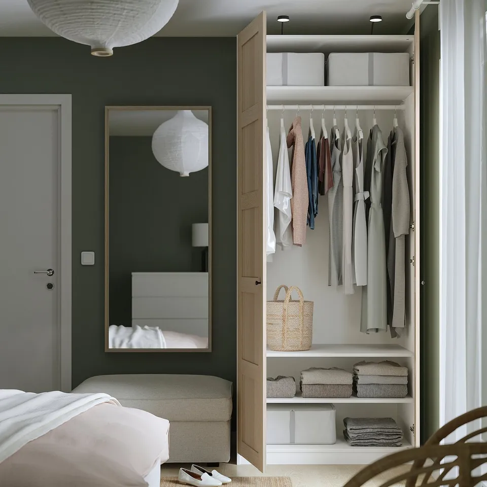 Open wardrobe with clothes, storage bins, and mirror.