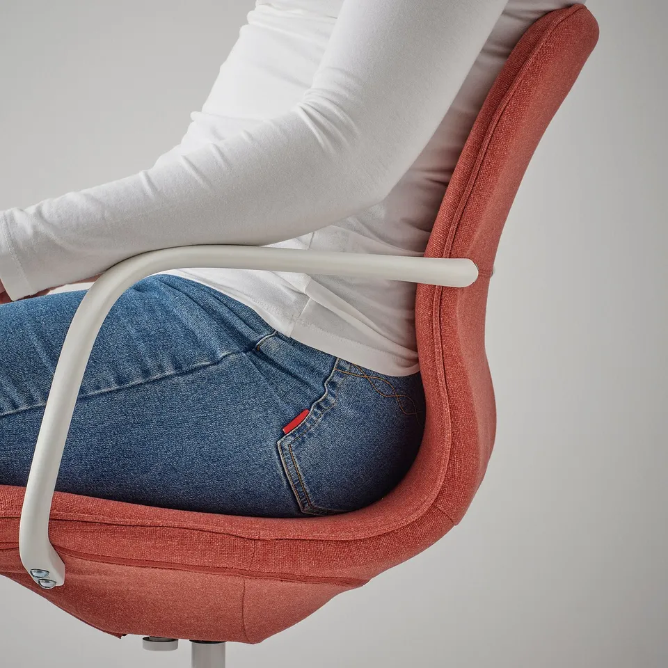Person sitting in a red office chair, slightly reclined, with armrests.