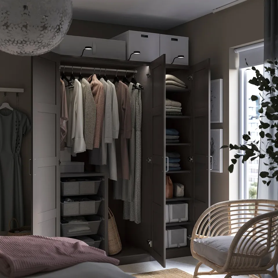 Modern bedroom with dark PAX wardrobe and wicker chair.
