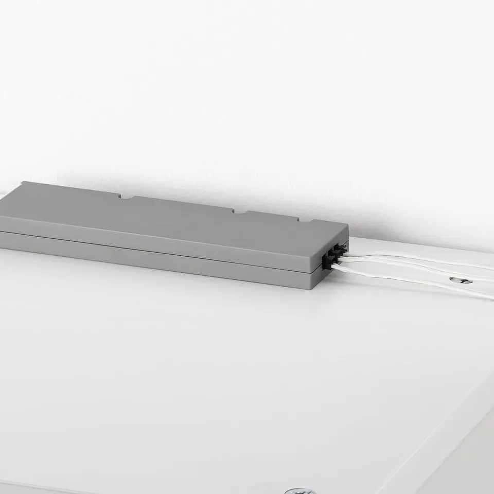 Grey TRÅDFRI led driver connected to white surface, enabling smart lighting control.