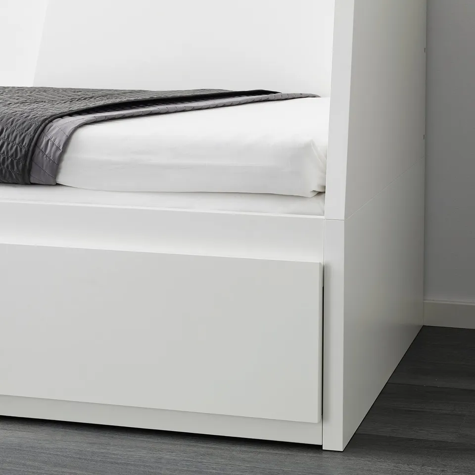 A FLEKKE daybed with a white frame, featuring two drawers beneath the mattress. It serves as a sofa and transforms into a double bed for guests.