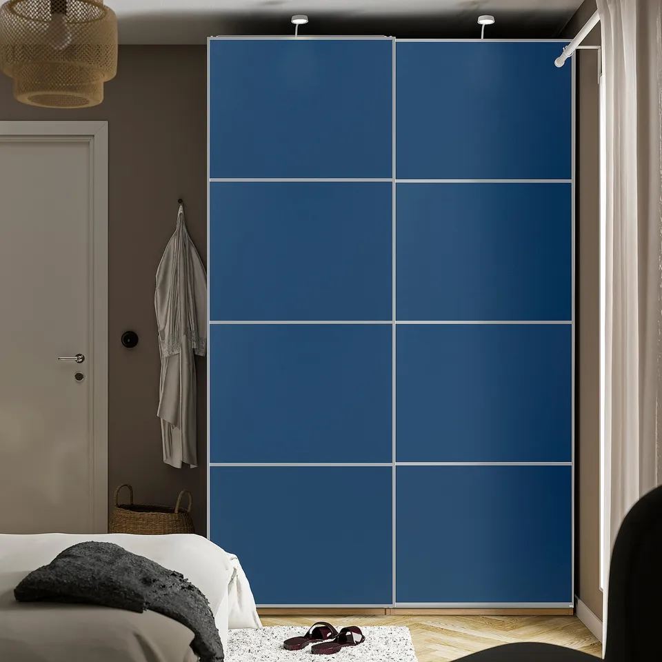 Large blue sliding closet doors in bedroom, matching bed frame, with shoes at base, robe hanging nearby.
