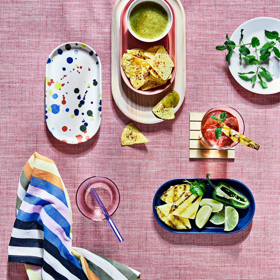 Colourful RÖDSNULTRA plates centre table setup with food and drinks.