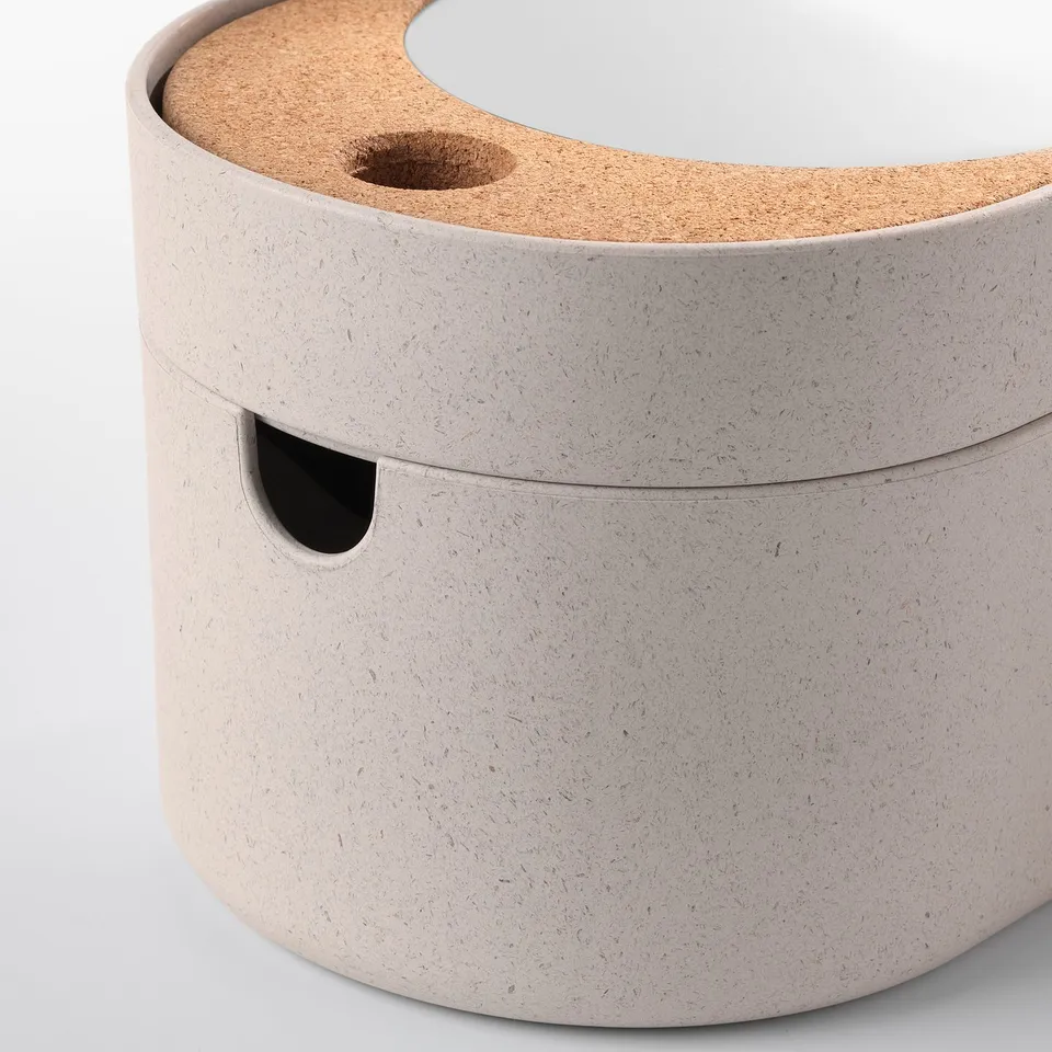 Round, beige storage box with cork lid, small cutouts, and integrated mirror inside. High-quality, practical design.