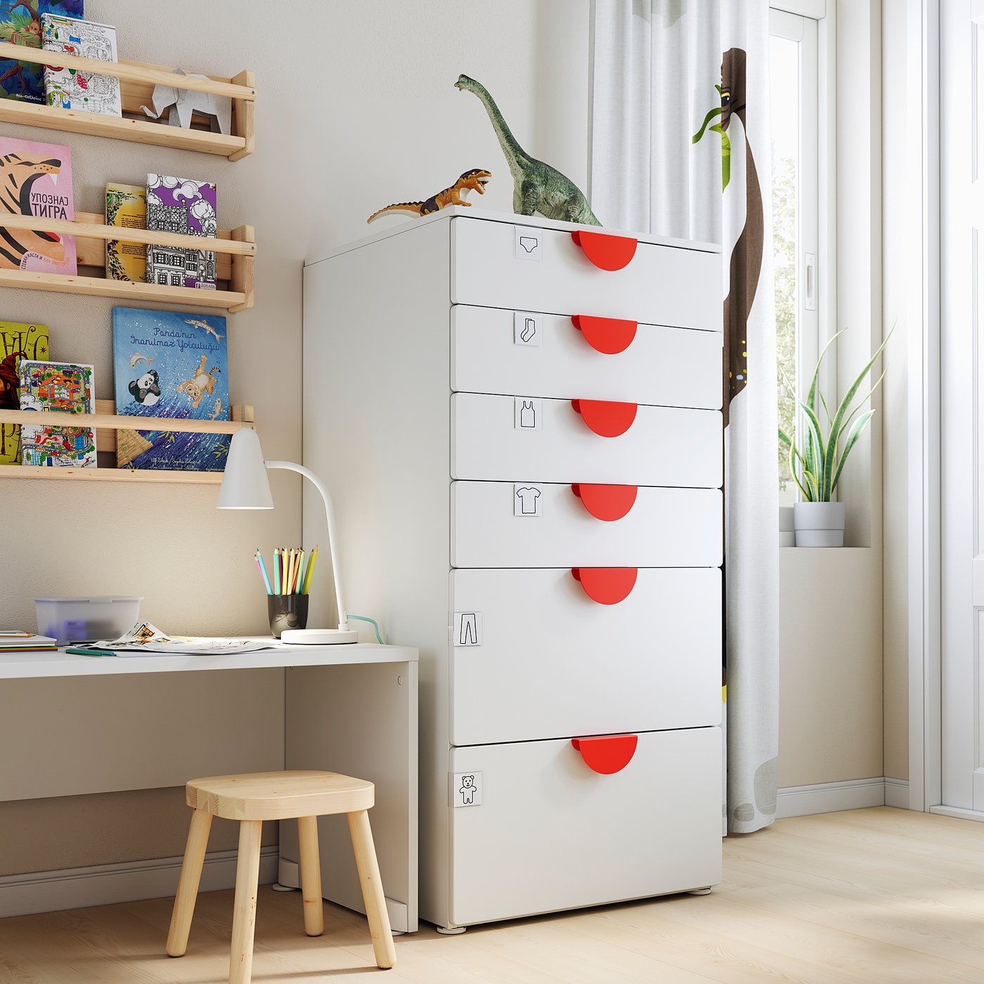 Kids room with SMÅSTAD chest, dino toys, books, desk, lamp, plant.