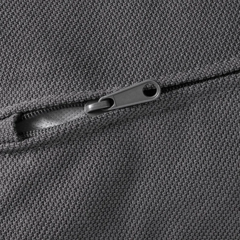 Close-up of durable, textured zip on grey, woven sofa cover. Focus on metal zip detail.
