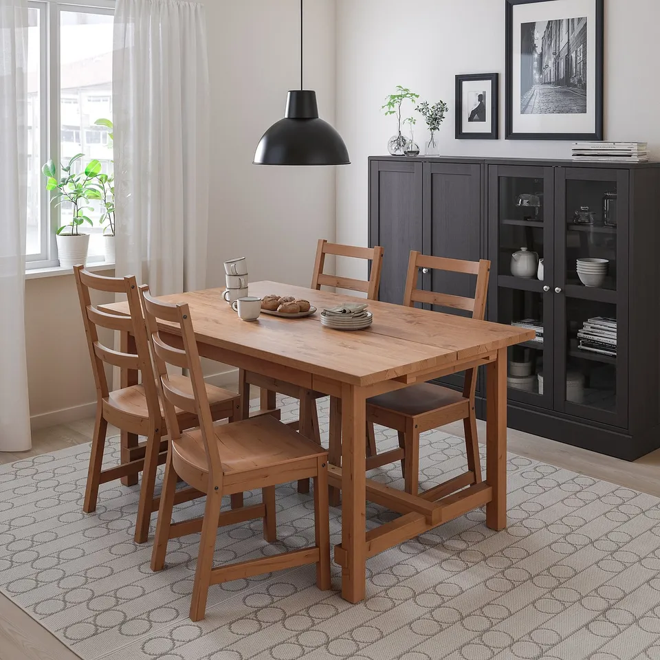 Small wooden dining set in corner, includes table & chairs. Surrounded by dark cabinet & window.