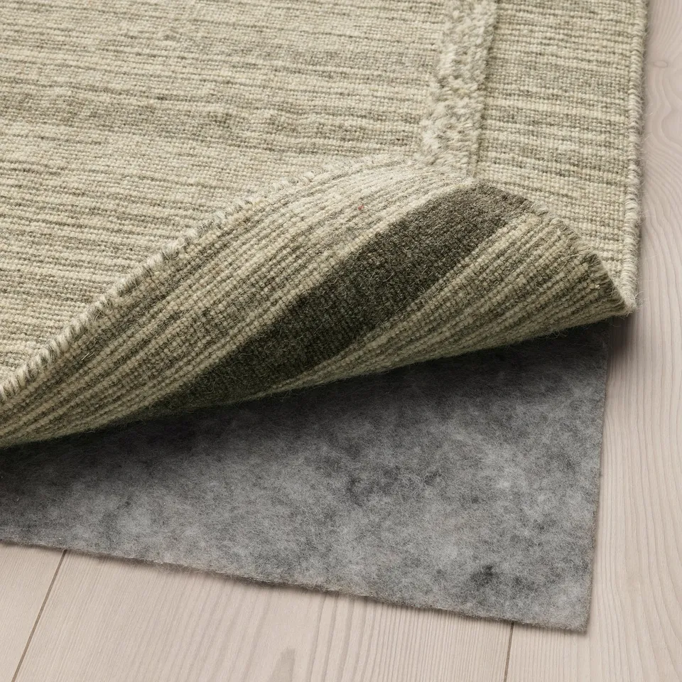 A rug underlay with anti-slip surface on a wooden floor, demonstrating its functionality.
