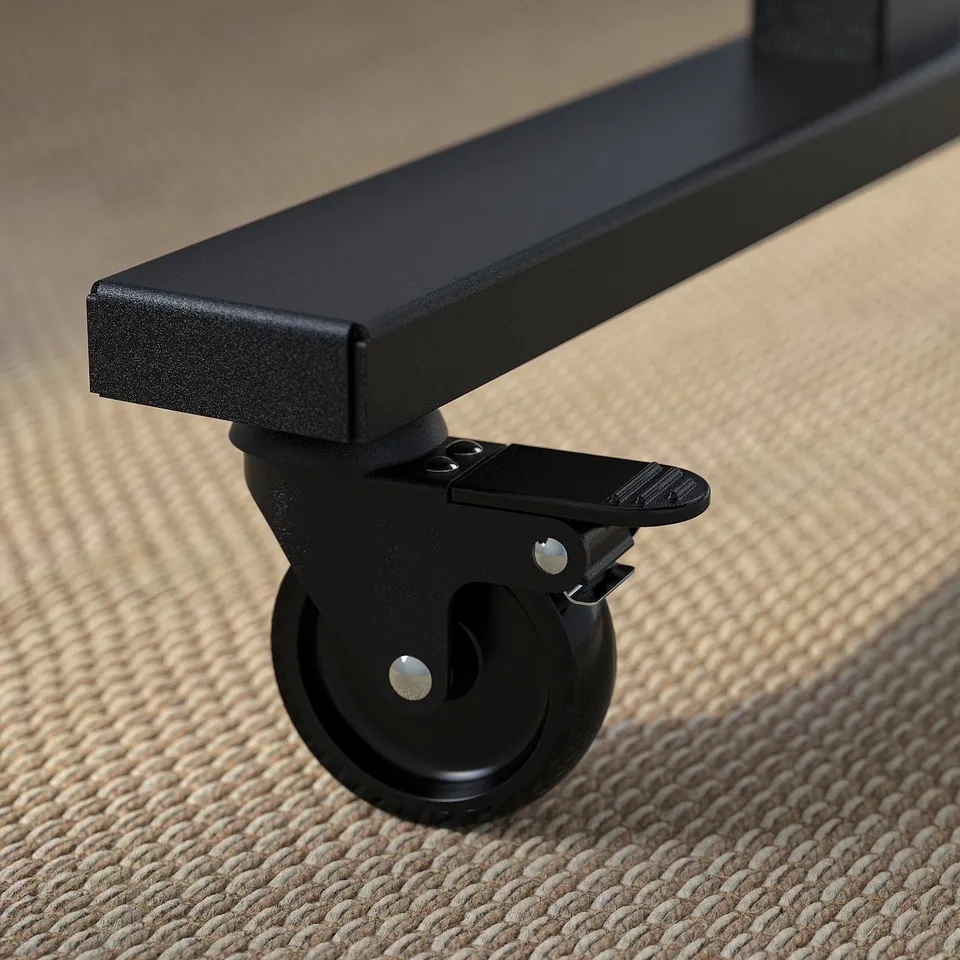 Close-up of a black office tables caster with locking mechanism on a brown woven rug.