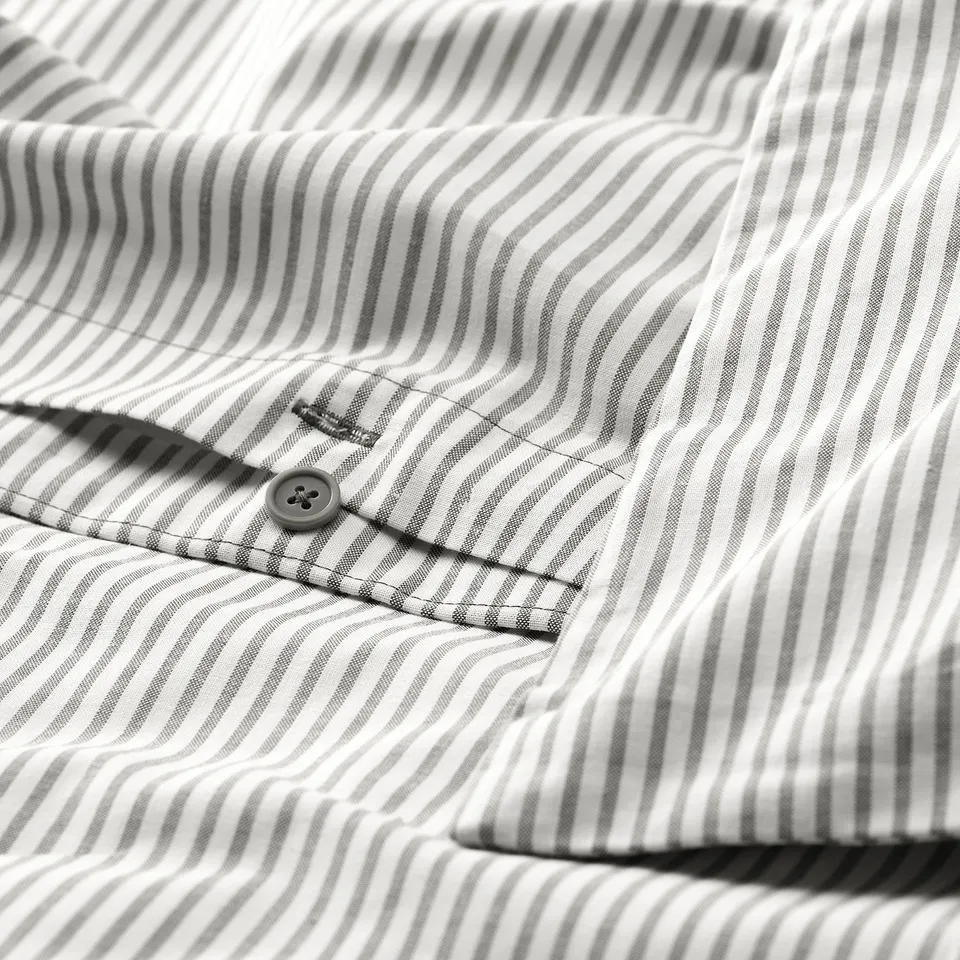 Close-up of striped fabric with visible button. Shows high thread count and detailed stitching.