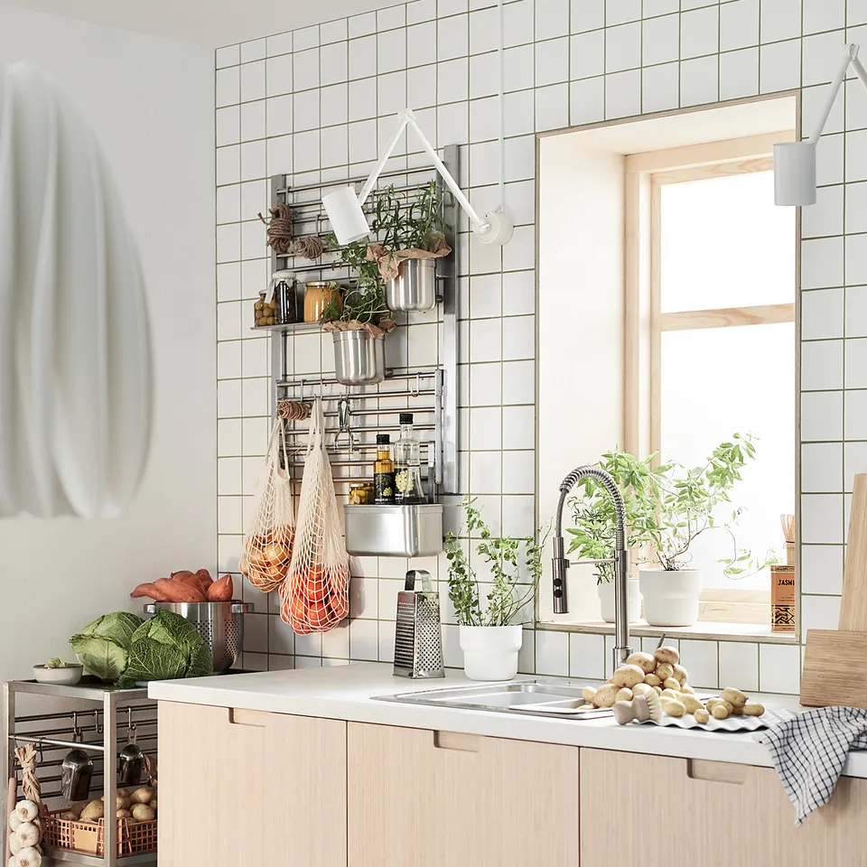Modern kitchen with bamboo FRÖJERED cabinets, white countertops, hanging green plants, and a large window.