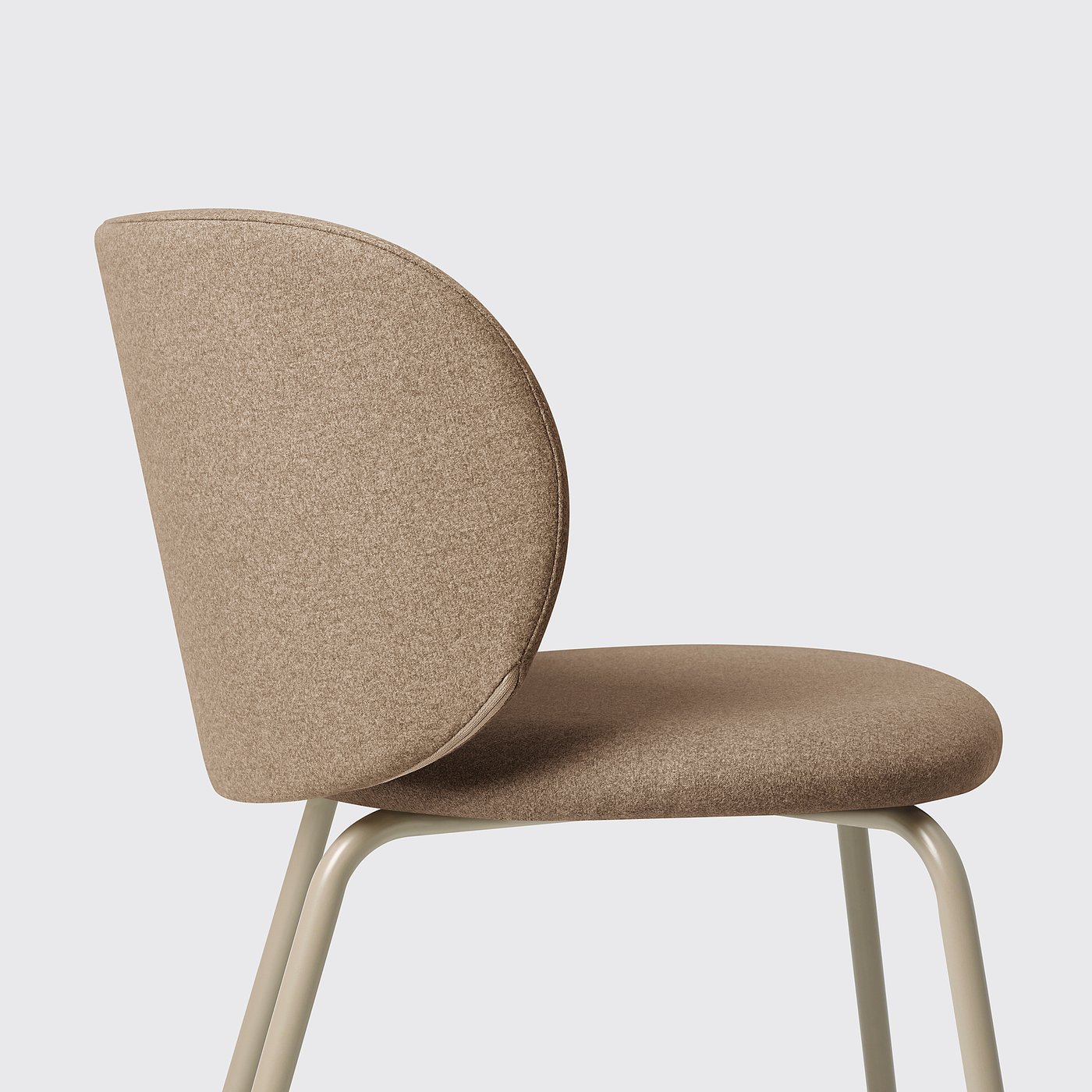 Modern chair with curved back and seat, light brown upholstery, sturdy tan metal legs.