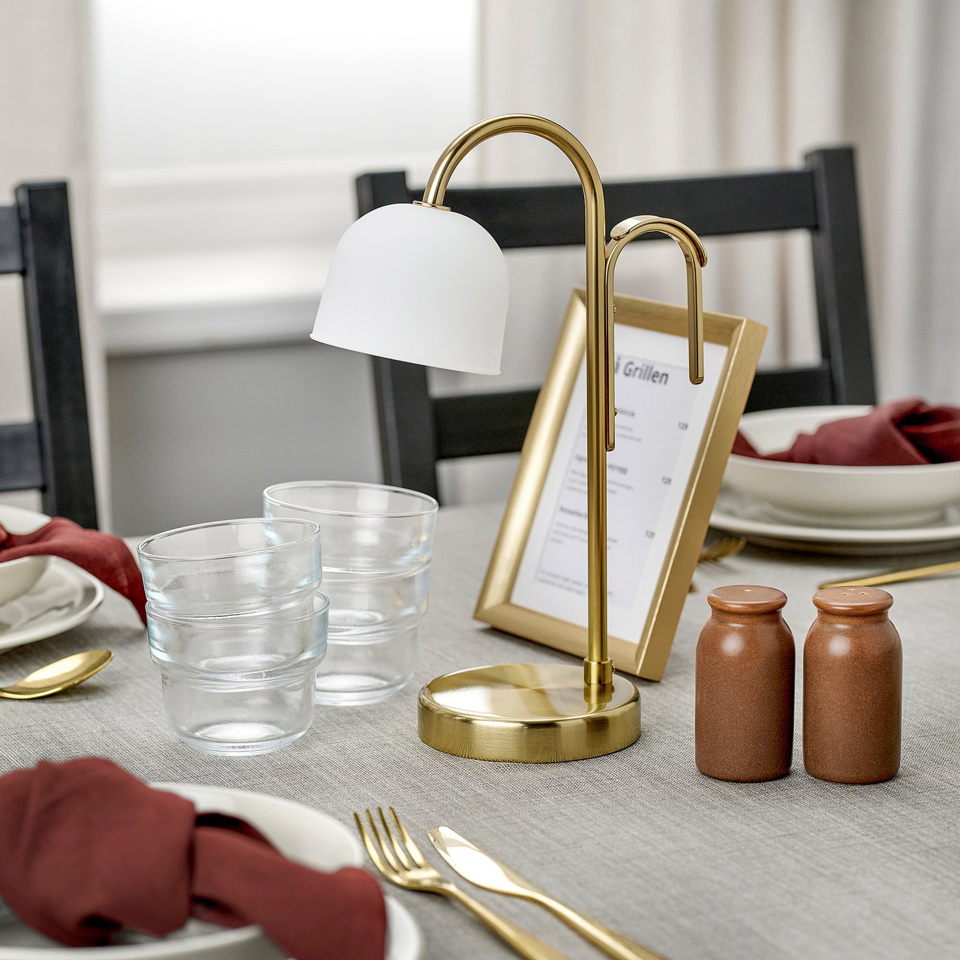 A stylish lamp sits on a dining table, lighting up a menu with a warm, diffused glow.