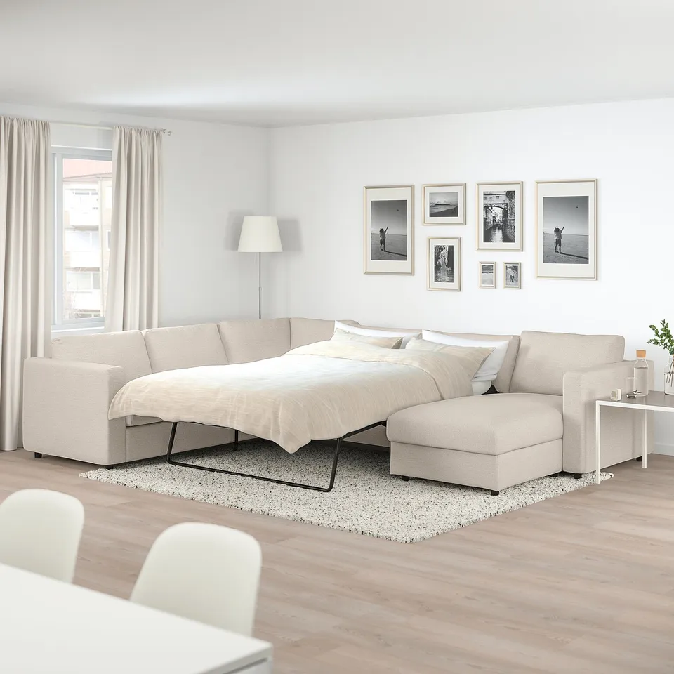 Modern living room with beige VIMLE sofa-bed, black legs, rug, & art.