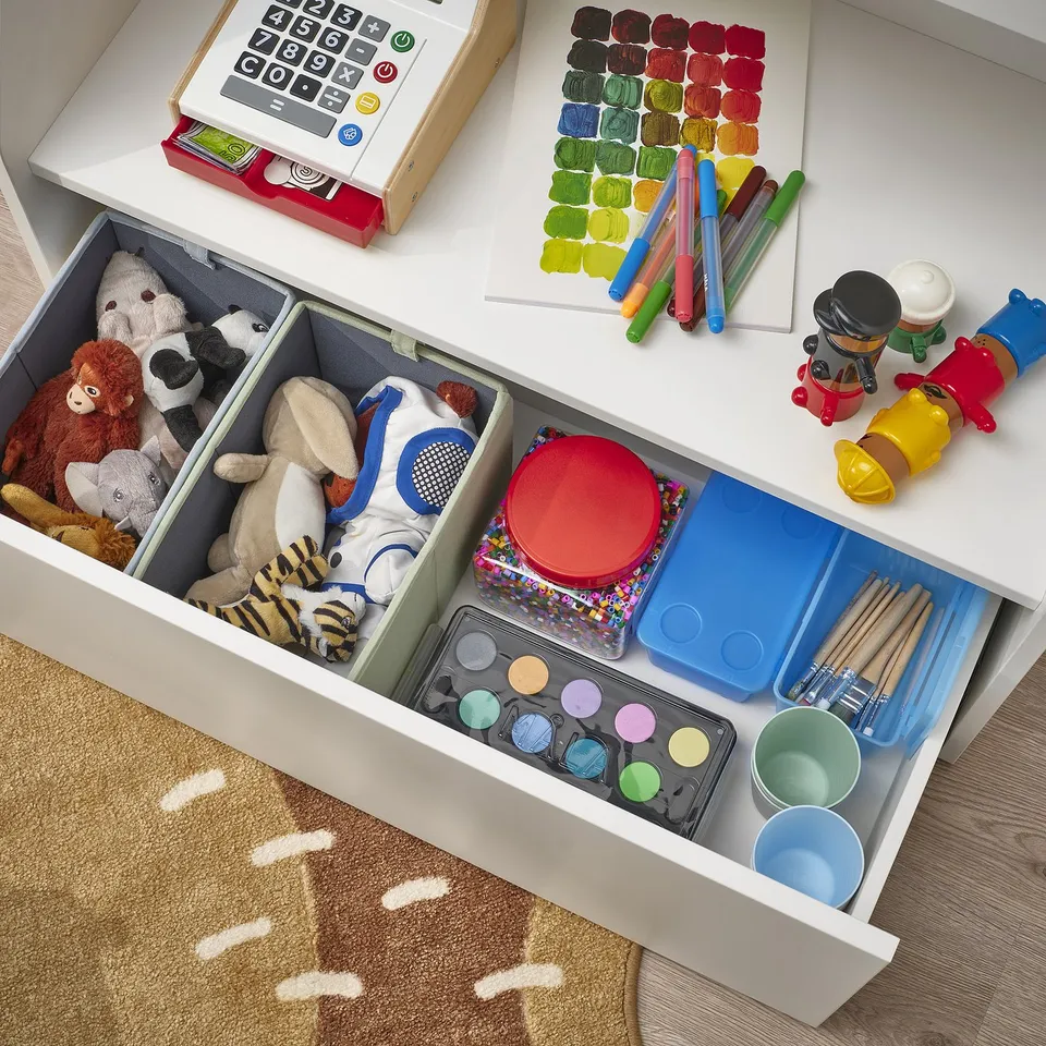 Open drawer with toys and supplies. Calculator and markers on top. Rounded corners for safety.