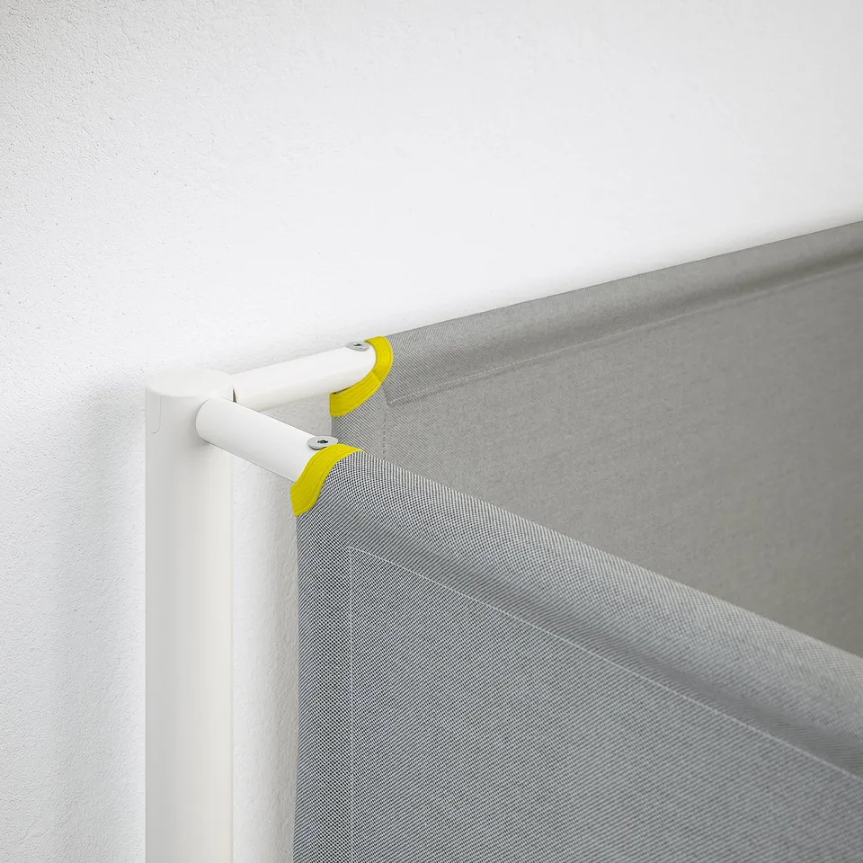 White curtain rod with lime end caps holding grey sheer curtain.
